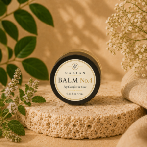 Carian Balm No.4 lip balm in a small black jar on a stone with greenery and dried flowers